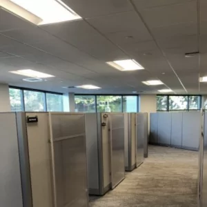 Modern office space featuring cubicles with sliding doors, designed for privacy and organization, showcasing natural light from large windows.